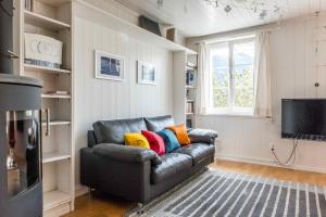 - un canapé en cuir avec des oreillers colorés dans le salon dans l'établissement Chalet Lienzhubel - GRIWA RENT AG, à Grindelwald