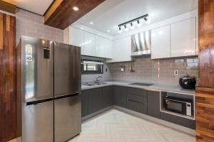 a kitchen with a stainless steel refrigerator and gray cabinets at The Some Plus Susan in Seogwipo