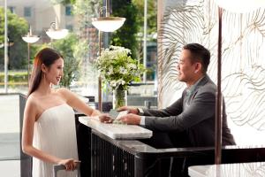 a man and a woman standing in front of a register at Momentus Hotel Alexandra in Singapore