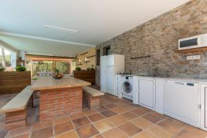 cocina con pared de piedra, lavadora y secadora en Armonia estudio, comparte exterior, en Llinars del Vallès