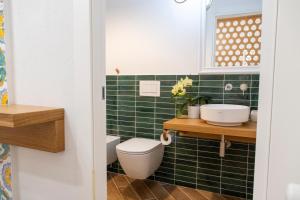Un baño con azulejos verdes, inodoro y lavabo. en Taonasi Taormina City Apartment, en Taormina