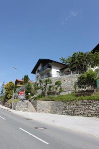 ein Haus auf einer Steinmauer neben einer Straße in der Unterkunft Panorama Appartements Mora - 3 Edelweiß Superior in Oetz