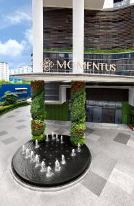 una fuente frente a un edificio con una señal en Momentus Hotel Alexandra en Singapur