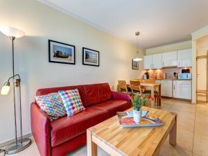 ein Wohnzimmer mit einem roten Sofa und einem Tisch in der Unterkunft Residenz am Balmer See - BS 36 mit Wellnessbereich in Balm