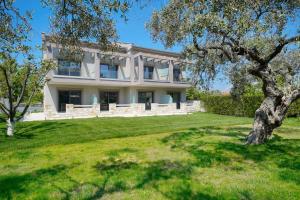 une grande maison blanche avec un arbre dans la cour dans l'établissement Yasemi Luxury Rooms, à Thasos