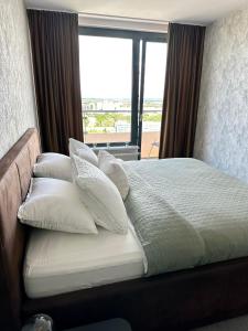 a bedroom with a bed with pillows and a window at Luxusný apartmán na 21 poschodí s parkovaním zadarmo BA in Bratislava +36 photos