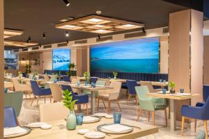 a restaurant with tables and chairs and a large screen at Melia Alicante in Alicante