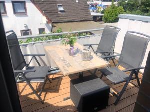een houten tafel en stoelen op een balkon met een tafel en bloemen bij Haus Sommerwind; Wohnung 3 in Sankt Peter-Ording
