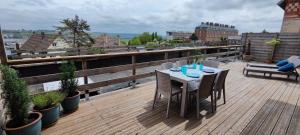 terraza de madera con mesa y sillas en el balcón en Escale Dieppe Gambetta - Appart et Studios 2-6 personnes Vue Ville et Mer, en Dieppe