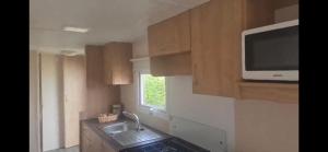 a small kitchen with a sink and a microwave at 192 Rickardos Holiday Lets 3 Bedroom caravan near Mablethorpe in Saltfleet
