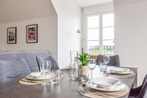 a dining room table with plates and glasses on it at Sur un Nuage by Plaza in Serris