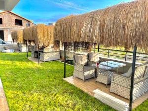 a patio with chairs and a table and a straw roof at ReynaBe Boutique Hotel in Dikili