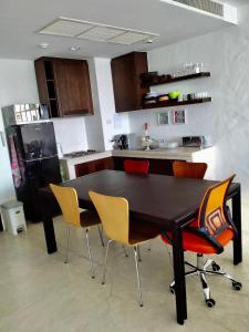 cocina con mesa negra con sillas y nevera en Las Tortugas, Cozy condominium on Khao Tao beach, Hua Hin, en Khao Tao