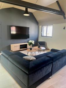 a large blue couch in a living room with a tv at Le Loft Manhattan, en centre ville, proche Sainte Bernadette avec Parking, PRIMO C0NCIERGERIE in Nevers