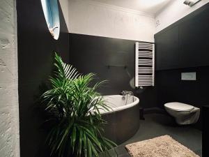a bathroom with a tub and a toilet and a plant at Apartament Centrum A in Wejherowo