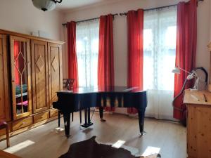 ブダペストにあるMatyas House in the City Centerの赤いカーテン付きの部屋の黒いピアノ