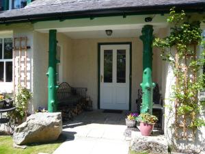 een voordeur van een huis met groene zuilen bij Ivy Cottage Bed and Breakfast in Braemar