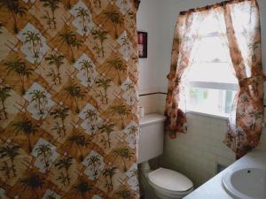 baño con aseo y papel pintado con palmeras en Mini Mansion Hotel affordable stays Plainfield NJ near public transportation, en Plainfield
