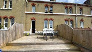 a wooden deck with a table and chairs in front of a building at Cozy coastguard cottage with sea views in East Cowes