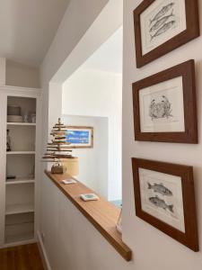 a hallway with paintings on the wall and a wooden shelf at Cozy coastguard cottage with sea views in East Cowes