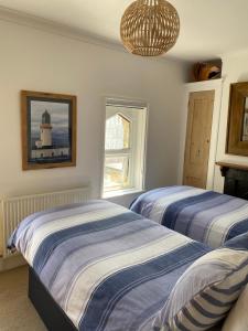 a bedroom with two beds and a window with a lighthouse at Cozy coastguard cottage with sea views in East Cowes