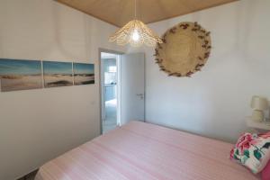 1 dormitorio con cama rosa y lámpara de araña en Casa da Avó en Alcácer do Sal
