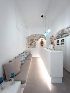 sala de estar con paredes blancas y sofá en Aggelikoula Rooms, en Tinos