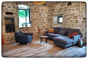 a living room with two couches and a stone wall at Hortense Grange 2/4 personnes in Sanilhac