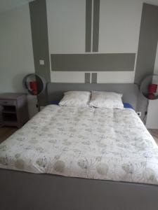 1 cama con colcha blanca y 2 almohadas en Chambre d'hôtes 84 de la Manelière, en La Flocellière