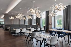 a dining room with tables and chairs and chandeliers at Courtyard by Marriott Munich Garching in Garching bei München