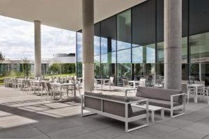 eine Terrasse mit Tischen und Stühlen vor einem Gebäude in der Unterkunft Courtyard by Marriott Munich Garching in Garching bei München