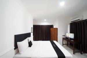 a bedroom with a bed and a desk with a television at DS Colive Marina in Semarang