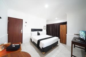 a bedroom with a bed and a desk and a television at DS Colive Marina in Semarang