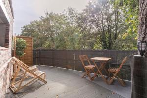 une terrasse avec 2 chaises, une table et une clôture dans l'établissement Sauna, jacuzzi, terrasse et parking, à Rouen
