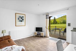 a living room with a couch and a television at The Clover Lodge, Red Lake Farm Nr Glastonbury in Somerton