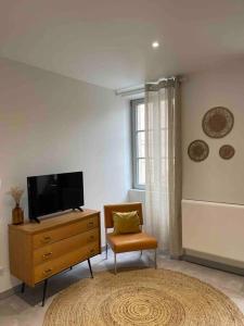 - un salon avec une télévision sur une commode et une chaise dans l'établissement Le cocon des ducs, appartement centre historique, à Nevers