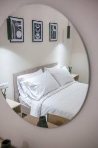 lustro z łóżkiem z białą pościelą i poduszkami w obiekcie Aurora apartments Room 1 w Marmari