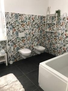 een badkamer met 2 toiletten en bloemenbehang bij Casa Gaiani Villetta in riva al lago vista mozzafiato in Varano Borghi