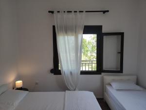 a bedroom with two beds and a window at Fyllio's Apartment in Vourvourou