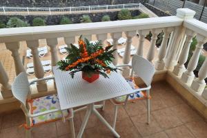 una mesa con un jarrón de flores en el balcón en Tropical Apartment - Heated Pool, en Palm-mar
