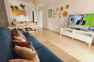 sala de estar con sofá azul y TV de pantalla plana en Tropical Apartment - Heated Pool, en Palm-mar