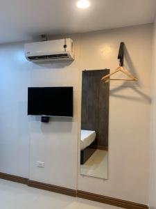 a wall with a tv and a mirror in a room at Maine City Residences in Manila +10 photos