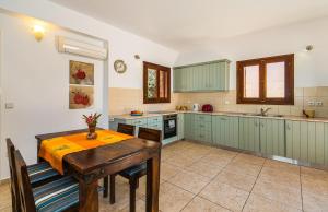 a kitchen with green cabinets and a wooden table at Lemonia Beach Villa in Stavros