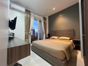 um quarto com uma cama grande e uma varanda em PURNAMA BALIGE HOTEL em Balige