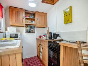 uma cozinha com armários de madeira e um forno com placa de fogão em Northgate Bakery Annex em Beccles