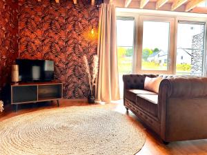 sala de estar con sofá marrón y TV en Hour House - Esc'Appart, en Houyet