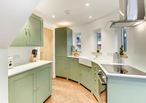 een keuken met groene kasten en witte aanrechtbladen bij Zeppelin in Woodbridge