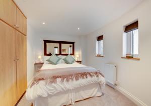 een witte slaapkamer met een groot bed en een spiegel bij Zeppelin in Woodbridge