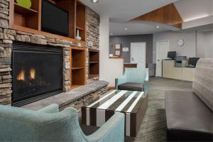 a living room with a fireplace and a couch and chairs at Residence Inn Chico in Chico