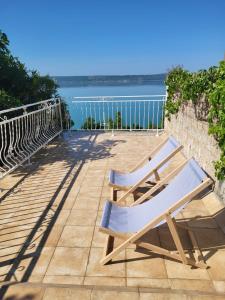 2 sedie sedute su un patio con vista sull'acqua di Rustic Home Maslenica a Maslenica